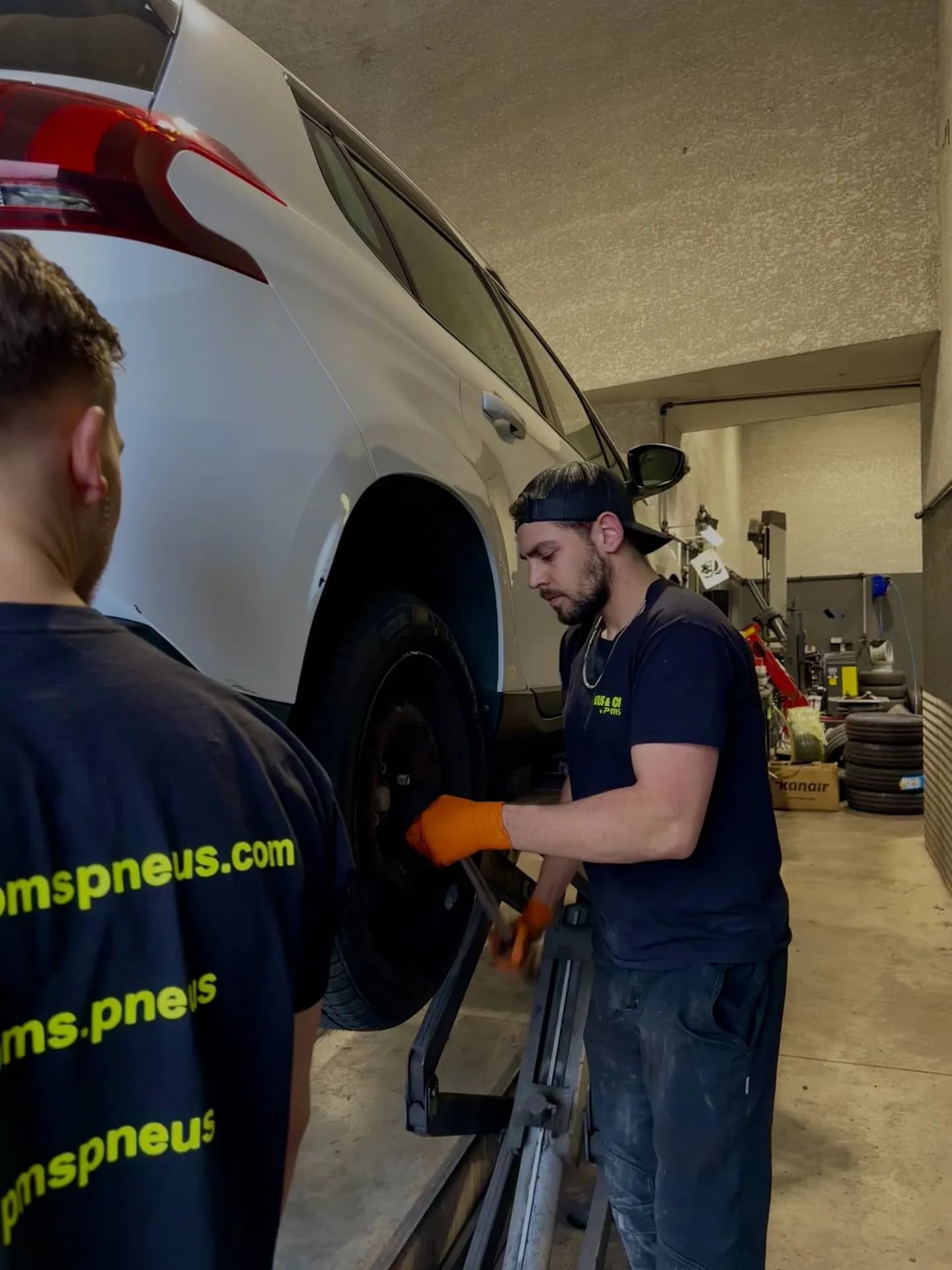 Deux techniciens PMS Pneus démontent une roue dans l'atelier