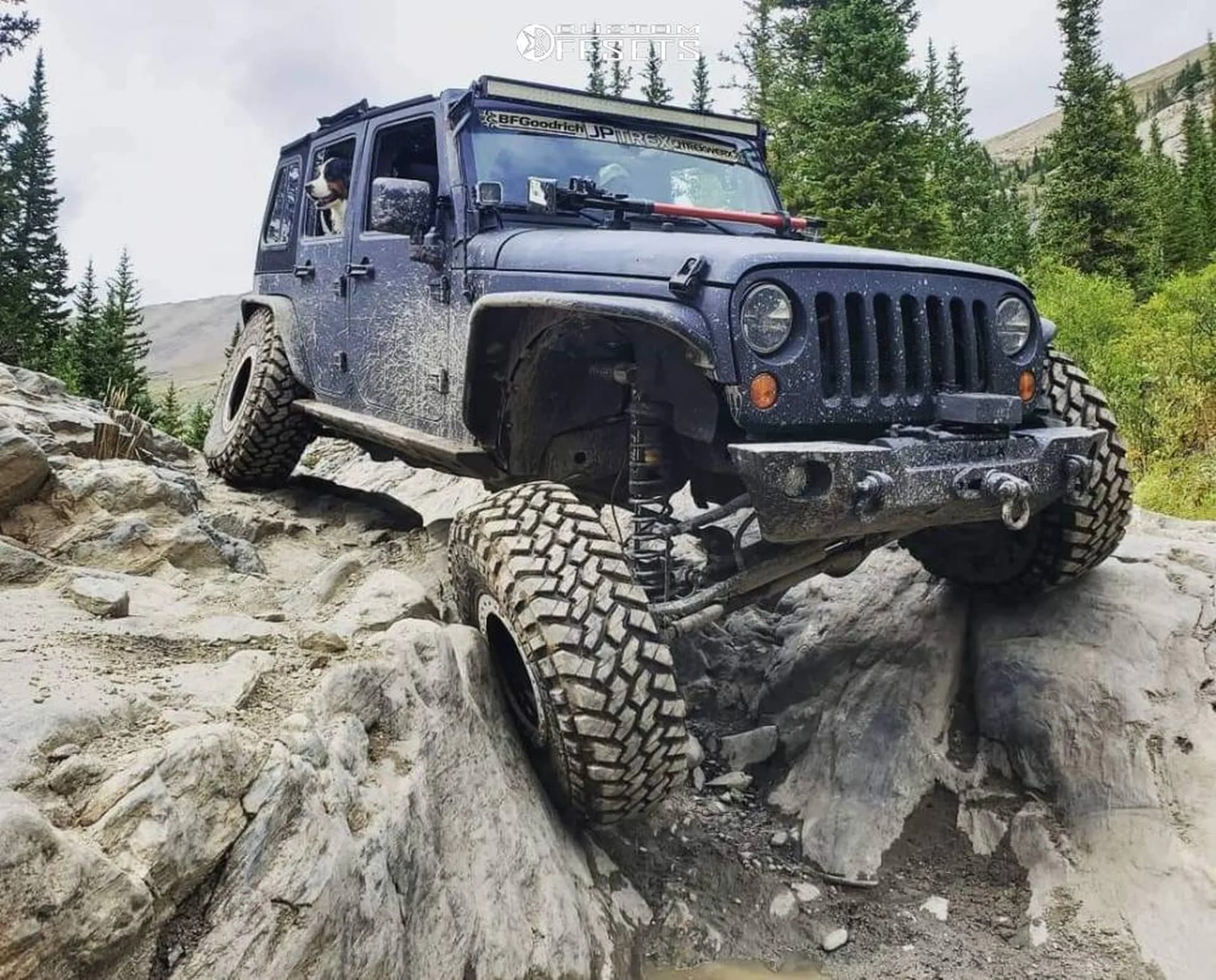 Un 4x4 franchit un passage rocheux sur des pneus tout-terrain.