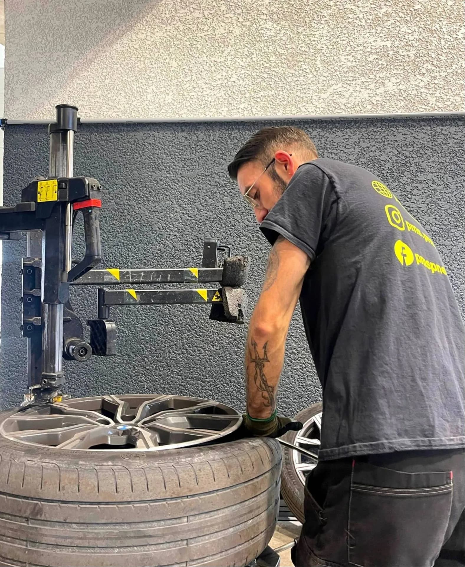 Un technicien démonte un pneu d'une jante alliage à la démonte-pneus.